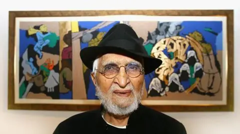 Getty Images Indian artist MF Husain wearing a black jacket with white shirt and a black hat poses in front of one of his paintings in Raan bar at the O2 Arena on July 3, 2007 in London